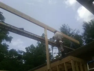 Carpenter setting a ridge beam over a new addition frame — Ice Dam Removal by Roofing Brothers in Oakfield