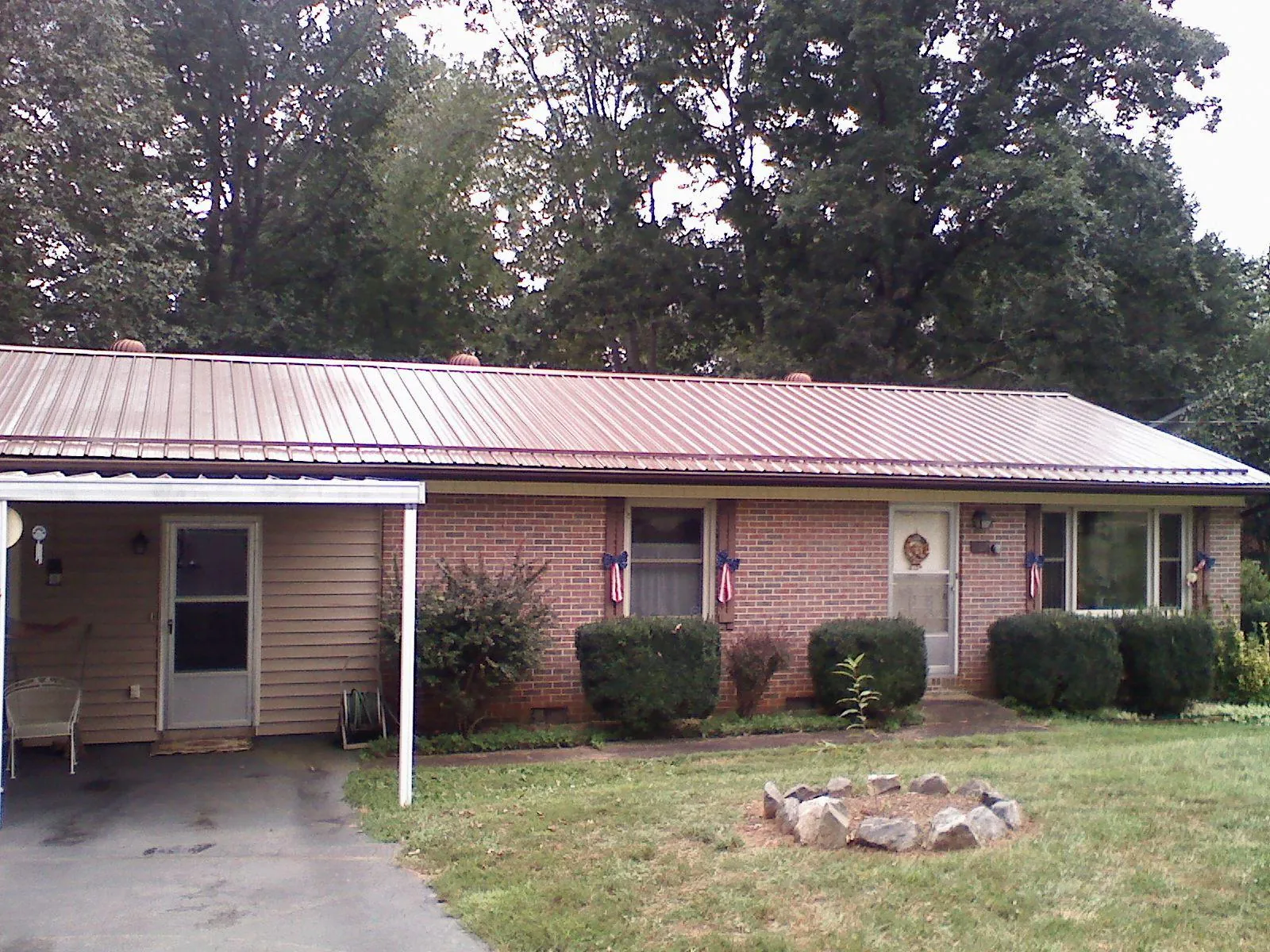 Bronze metal roof and carport on a brick ranch home — Roof Repair work by our crew in Oakfield